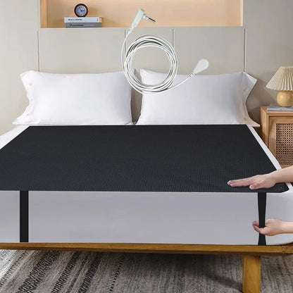 Person using a grounding sheet bed cover to cover a bed in a bedroom setting for grounding, showing the elastic to put in the mattress and the grounding cord