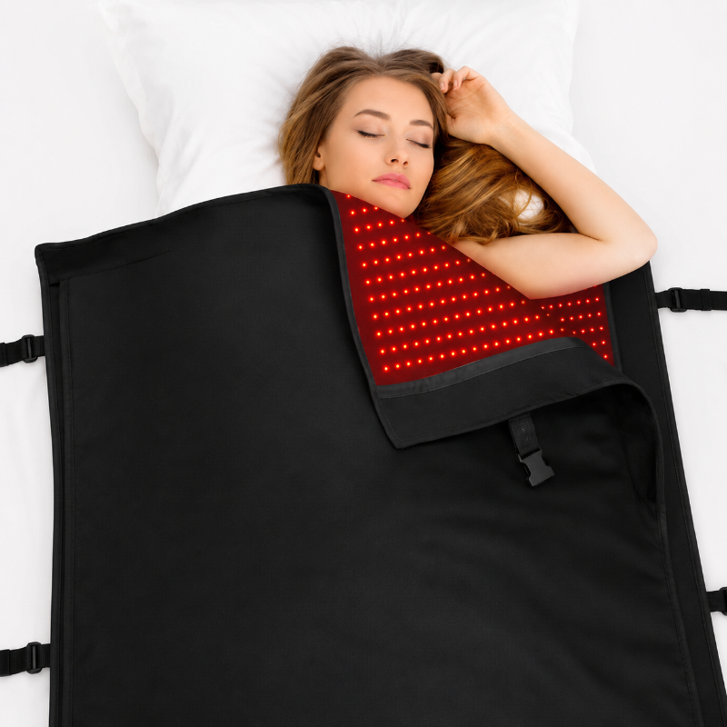 Woman lying on a black mat with red LED lights, receiving a treatment.